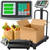 A digital scale with a platform, a display unit, and a cardboard box with groceries in paper bags. Voir les images du produit