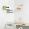 A corner of a room with floating shelves holding books and a desk with a laptop and clock. Anteprima dell’immagine prodotto