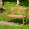 A wooden garden bench sits on grass next to a stone path, with trees in the background. Voir les images du produit