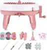 A pink and white knitting machine with various accessories laid out below it. Náhled obrázku produktu