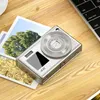 A digital camera is placed on a wooden desk next to some photographs and a laptop keyboard. Produktbild-Vorschau