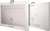 The image shows the packaging of a Guess 13'' laptop sleeve for MacBooks. The packaging is a white box with a clear window displaying the pink Saffiano patterned sleeve with a gold Guess logo. Anteprima dell’immagine prodotto