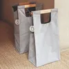 Two grey recycling bags with wooden handles are placed on a textured rug next to a wall. Náhľad obrázku produktu