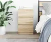 A bedside table with three drawers is placed next to a bed in a bedroom. Anteprima dell’immagine prodotto