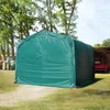 A green tent-like structure, possibly a storage shed or shelter, is set up outdoors in a grassy area with trees in the background. A tractor is visible to the left, and a red truck is partially visible under a wooden shelter to the right. Voir les images du produit