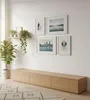 A living room scene featuring a wooden media console with framed artwork and plants on the wall. Produktbild-Vorschau