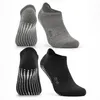 Four socks, two grey and two black, are displayed against a white background. The socks have grip dots on the soles. Produktbild-Vorschau