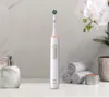A white electric toothbrush with a green brush head is displayed on a bathroom counter next to a soap dispenser and rolled towels. Produktbild-Vorschau