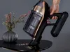 A hand holding a cordless vacuum cleaner over a table with some debris. Produktbild-Vorschau
