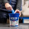 A person is pulling a blue cleaning wipe from a blue bucket of hand cleaner towels. Náhled obrázku produktu