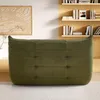 A green upholstered ottoman is placed on a light-colored rug in front of a bookshelf. Produktbild-Vorschau