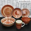 A collection of ceramic dishes and a mug with a striped pattern, arranged on a dark surface against a brick-like background. Náhled obrázku produktu