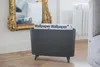 A dark gray magazine rack with a magazine inside, placed on a wooden floor in front of a decorative mirror and a radiator. Podgląd zdjęcia produktu