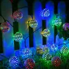 Decorative string lights with spherical bulbs are attached to a white picket fence and draped over grass. Produktbild-Vorschau