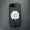 The back of a black iPhone case with a white wireless charger attached, lying on a dark gray textured surface. Anteprima dell’immagine prodotto