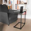 A laptop sits on a C-shaped side table next to a gray armchair in a room with bookshelves. Produktbild-Vorschau
