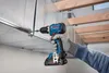 A person wearing a glove is using a cordless drill to attach a metal duct to a ceiling. Náhled obrázku produktu