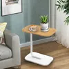 C-förmiger Endtisch aus hellem Holz und Weiß neben einem grauen Sofa, mit Kaffeetasse und Topfpflanze Voir les images du produit