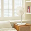 A white fan stands on a wooden bedside table next to a bed with a white pillow. Podgląd zdjęcia produktu