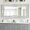 A large decorative mirror with a crystal frame and Celtic knot accents is mounted above a grey vanity with marble countertops in a bathroom. Produktbild-Vorschau