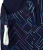 Close-up of a dark blue backpack with a geometric pattern of blue and purple lines. Features include a zippered pocket with a white and iridescent pull tab, and two zipper pulls with the brand name "Satch" printed on them. Voir les images du produit