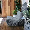 A gray sofa is placed on a wooden deck with plants in the background. Anteprima dell’immagine prodotto