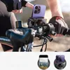 A person's hands wearing cycling gloves are shown adjusting a smartphone mounted on a bicycle handlebar. The smartphone is purple and appears to be an iPhone. Produktbild-Vorschau