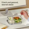 A person's hand holding a fork over a glass meal prep container on a desk next to a computer monitor. Anteprima dell’immagine prodotto