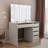 A white vanity table with a large illuminated mirror, drawers, and makeup items on top, set in a room with curtains and a floor lamp. Voir les images du produit
