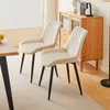 Two beige dining chairs are placed next to a wooden dining table, with a wooden cabinet in the background. Produktbild-Vorschau