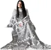 A woman is sitting and wrapped in a blanket with sleeves. Produktbild-Vorschau