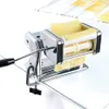A pasta maker is shown on a glass surface, with pasta dough being fed through it. Podgląd zdjęcia produktu