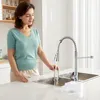 A woman is using a kitchen faucet in a modern kitchen. Podgląd zdjęcia produktu
