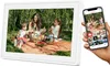 A family is having a picnic in a park, with a digital photo frame displaying a picture of the family and a smartphone showing the same picture. Náhled obrázku produktu