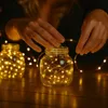 Hands arranging fairy lights in a glass jar. Produktbild-Vorschau