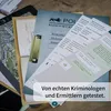 A collection of documents, including a map, official-looking papers, and a phone screen displaying a chat conversation, are spread out on a wooden surface. A gold clipboard is clipped to one of the documents. A text overlay reads 'Von echten Kriminologen u Produktbild-Vorschau