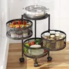 A rotating kitchen cart with three tiers, filled with various food items and kitchenware, placed on a wooden floor against a tiled wall. Produktbild-Vorschau