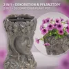 A decorative planter in the shape of a woman's head, filled with purple petunias, is shown with a close-up of the planter's opening and a smaller inset image of the planter with flowers. Náhled obrázku produktu