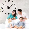 A family is posing in front of a large wall clock. Produktbild-Vorschau