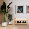 A shoe rack with a bench and cushions is placed in a hallway with plants and artwork on the wall. Produktbild-Vorschau