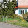 A chain-link fence and gate in front of a house with trees and bushes. Anteprima dell’immagine prodotto