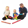 A woman, a young girl, and a toddler are sitting on the floor playing with colorful musical tubes. Náhled obrázku produktu