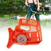 A person is holding a string trimmer in the background, while an orange starter assembly is in the foreground. Náhľad obrázku produktu