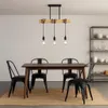 A dining room scene with a wooden table and four black chairs, illuminated by a pendant light fixture. Produktbild-Vorschau