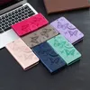 A collection of butterfly-embossed phone cases arranged on a dark surface next to a laptop. Produktbild-Vorschau