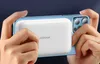 Hands holding a smartphone with a power bank attached to the back. Podgląd zdjęcia produktu