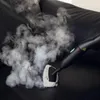 A handheld steam cleaner is being used to clean a black surface, possibly upholstery, with steam being emitted. Anteprima dell’immagine prodotto