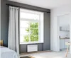 A bedroom with a large window, curtains, and a visible heating unit mounted on the wall below the window. Anteprima dell’immagine prodotto