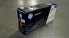 A yellow HP LaserJet toner cartridge box sits on a concrete floor. Náhľad obrázku produktu
