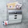 A modern stainless steel mailbox mounted on a concrete wall, containing mail and a rolled-up newspaper. Produktbild-Vorschau